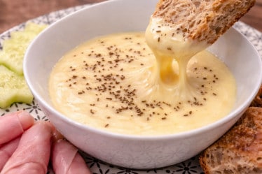 Kochkäse mit Brot in einem Schälchen mit Kochschinken, Brot und Salatgurke