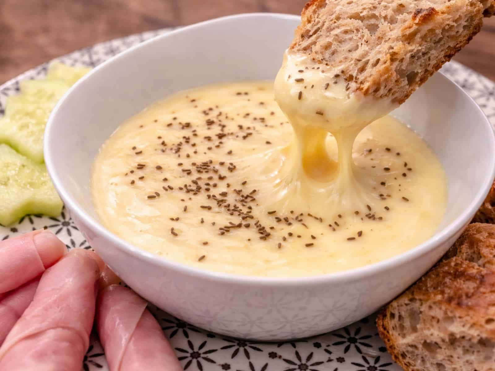 Kochkäse mit Brot in einem Schälchen mit Kochschinken, Brot und Salatgurke