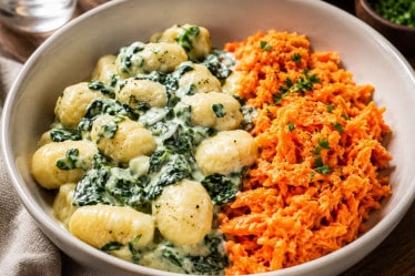 Cremige Gnocchi mit Spinat und Möhrensalat auf einem Teller