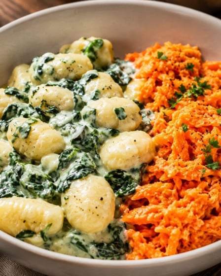 Cremige Gnocchi mit Spinat und Möhrensalat auf einem Teller