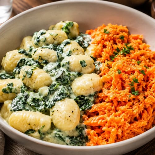 Cremige Gnocchi mit Spinat und Möhrensalat auf einem Teller