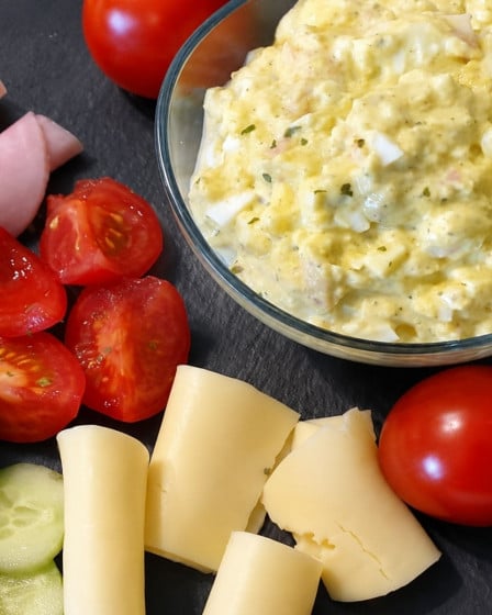 Eiersalat selbstgemacht, angerichtet mit Schinken, Käse, Tomaten und Gurken