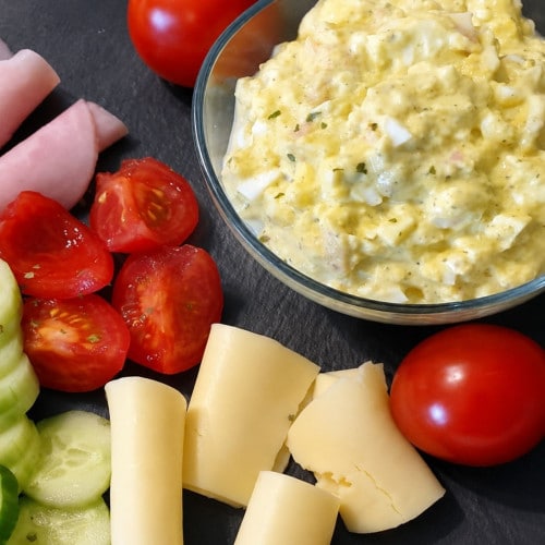 Eiersalat selbstgemacht, angerichtet mit Schinken, Käse, Tomaten und Gurken