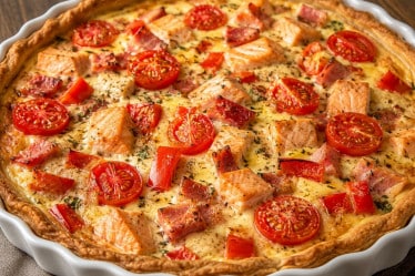 Quiche mit Lachs, Paprika, Tomaten und Schinken in einer Auflaufform