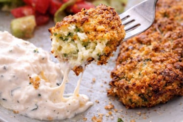 Feta-Zucchini-Taler mit Dip und Salat auf einem Teller
