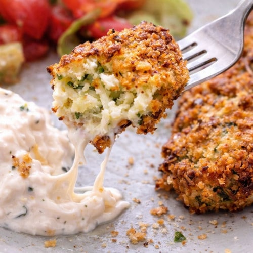 Feta-Zucchini-Taler mit Dip und Salat auf einem Teller