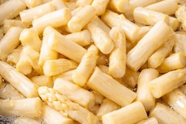 Weisse Spargelstücke in einem Topf mit sprudelndem Wasser