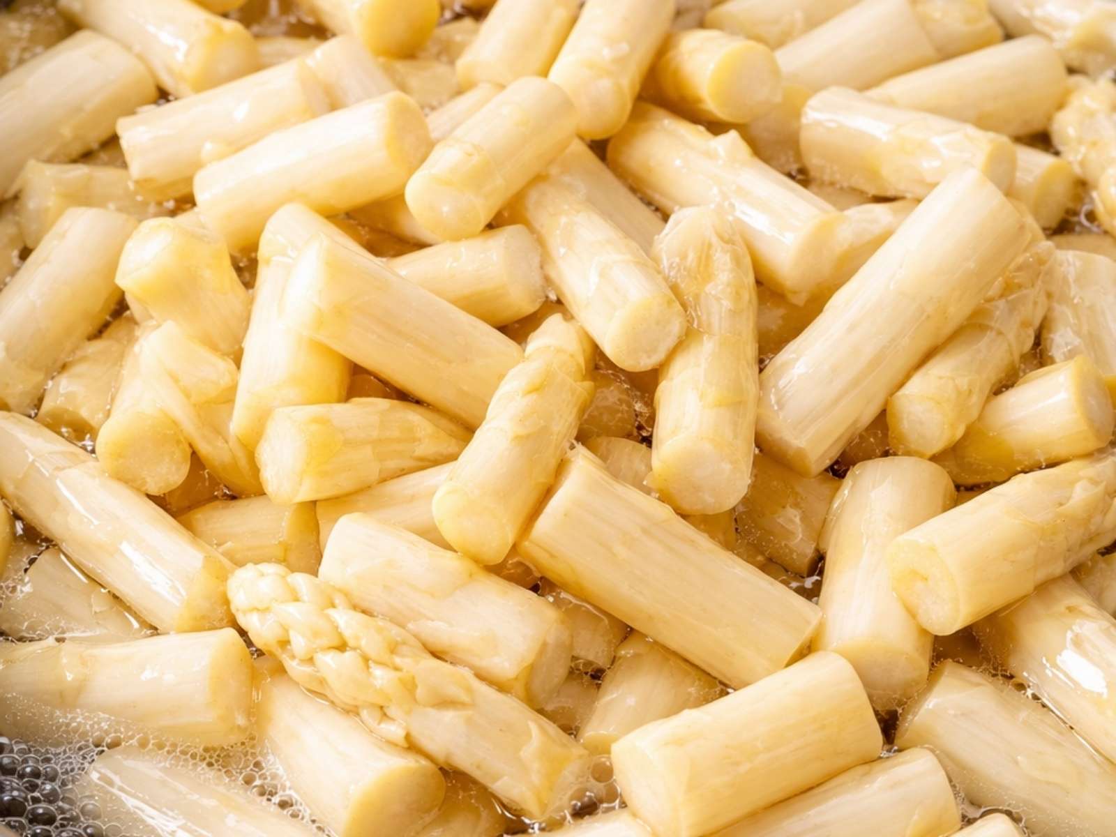 Weisse Spargelstücke in einem Topf mit sprudelndem Wasser