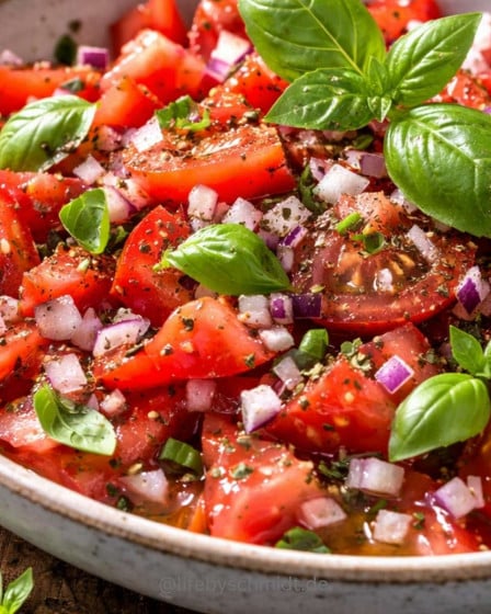 Einfacher klassischer Tomatensalat mit roten Zwiebeln, Olivenöl und frischem Basilikum
