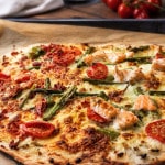 Spargelflammkuchen mit Lachs und Tomaten auf einem Ofenblech